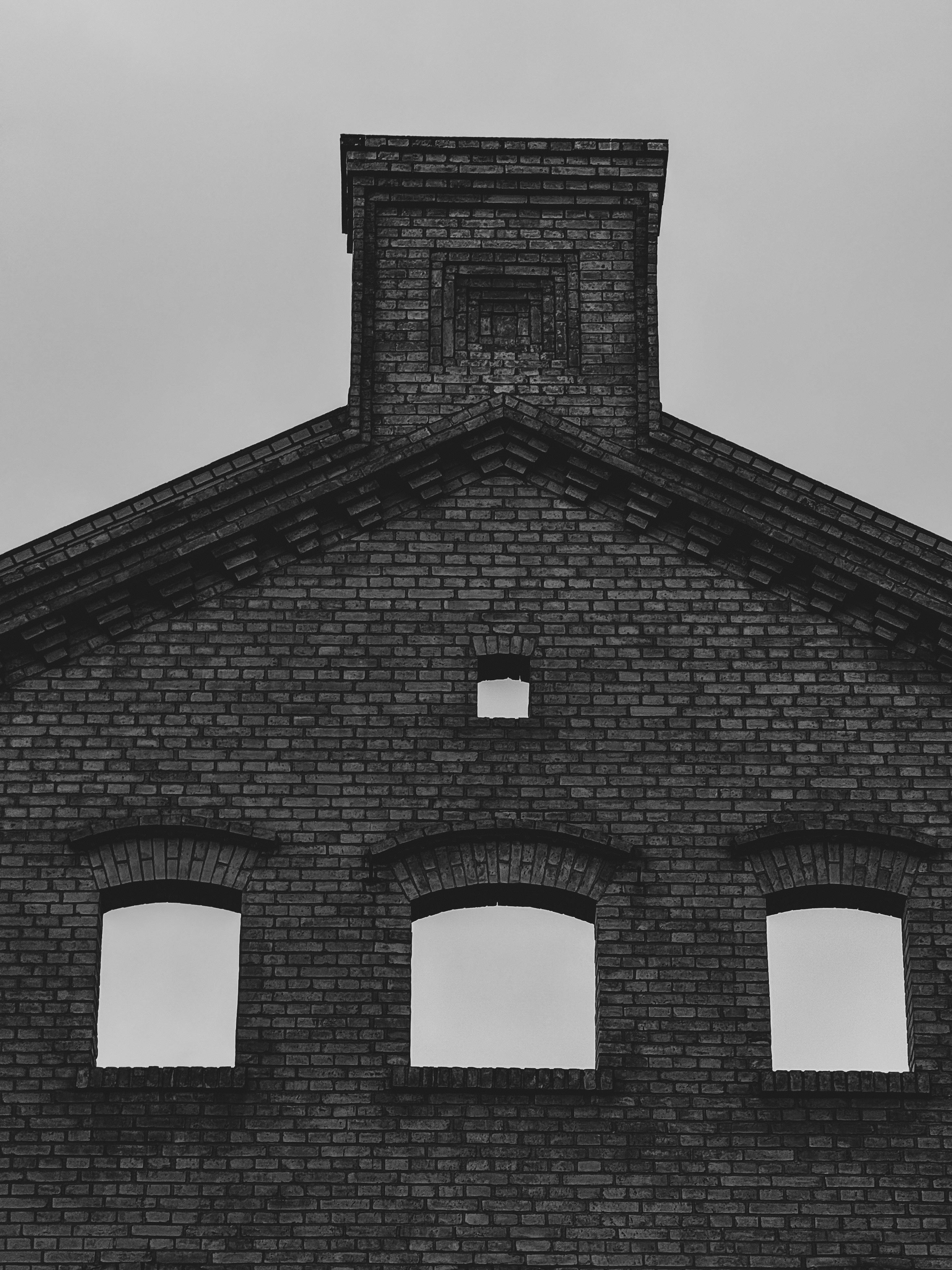 Kostnadsfria Svartvitt foto av en historisk tegelbyggnadsfasad med tomma fönster. Stock foto