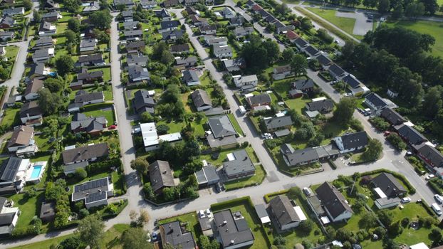 Aerial shot of a lush suburban neighborhood with green gardens and houses.