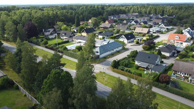 Aerial view of suburban houses surrounded by lush greenery in a Swedish neighborhood.