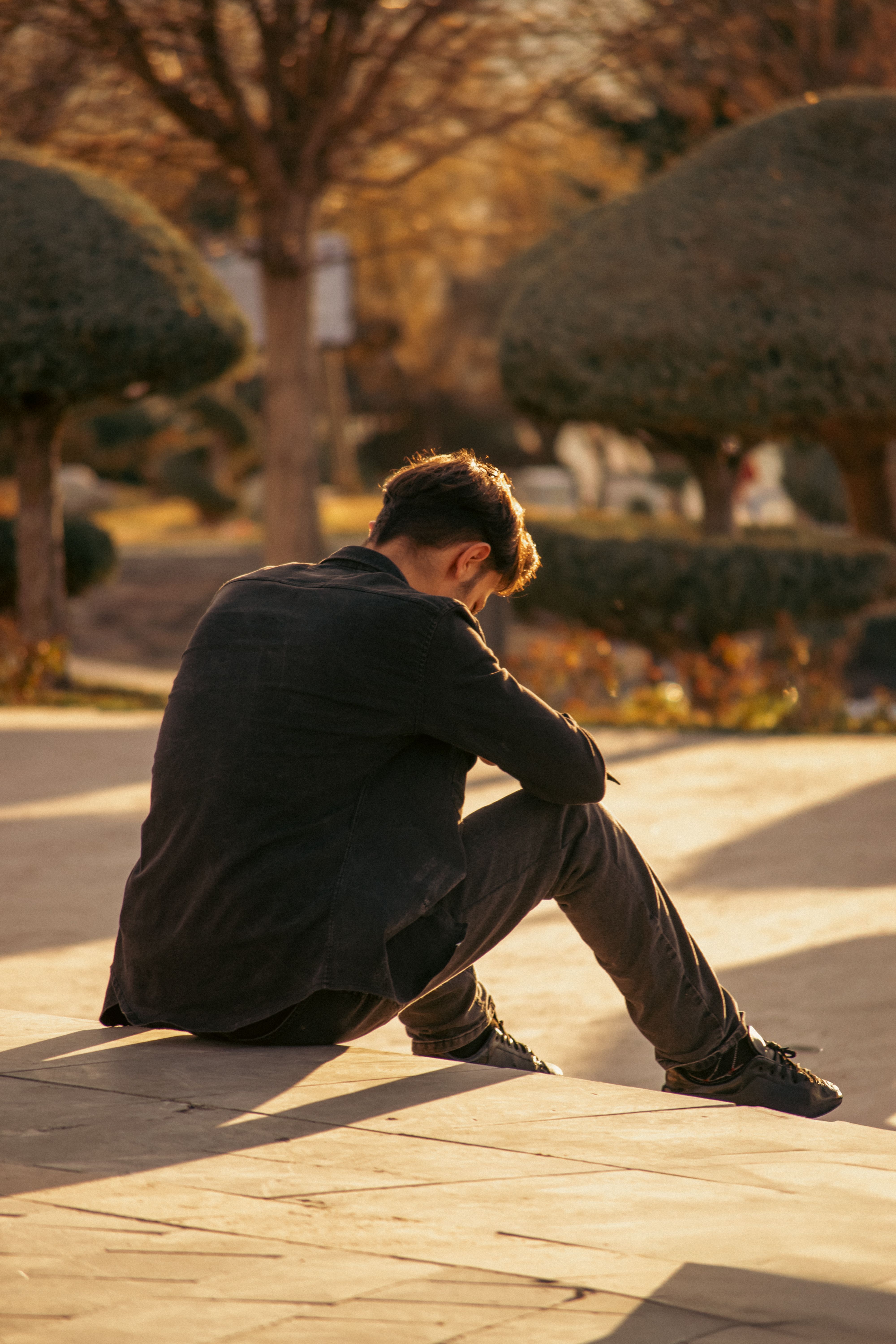 Contemplative Moment in Sunlit Urban Park · Free Stock Photo