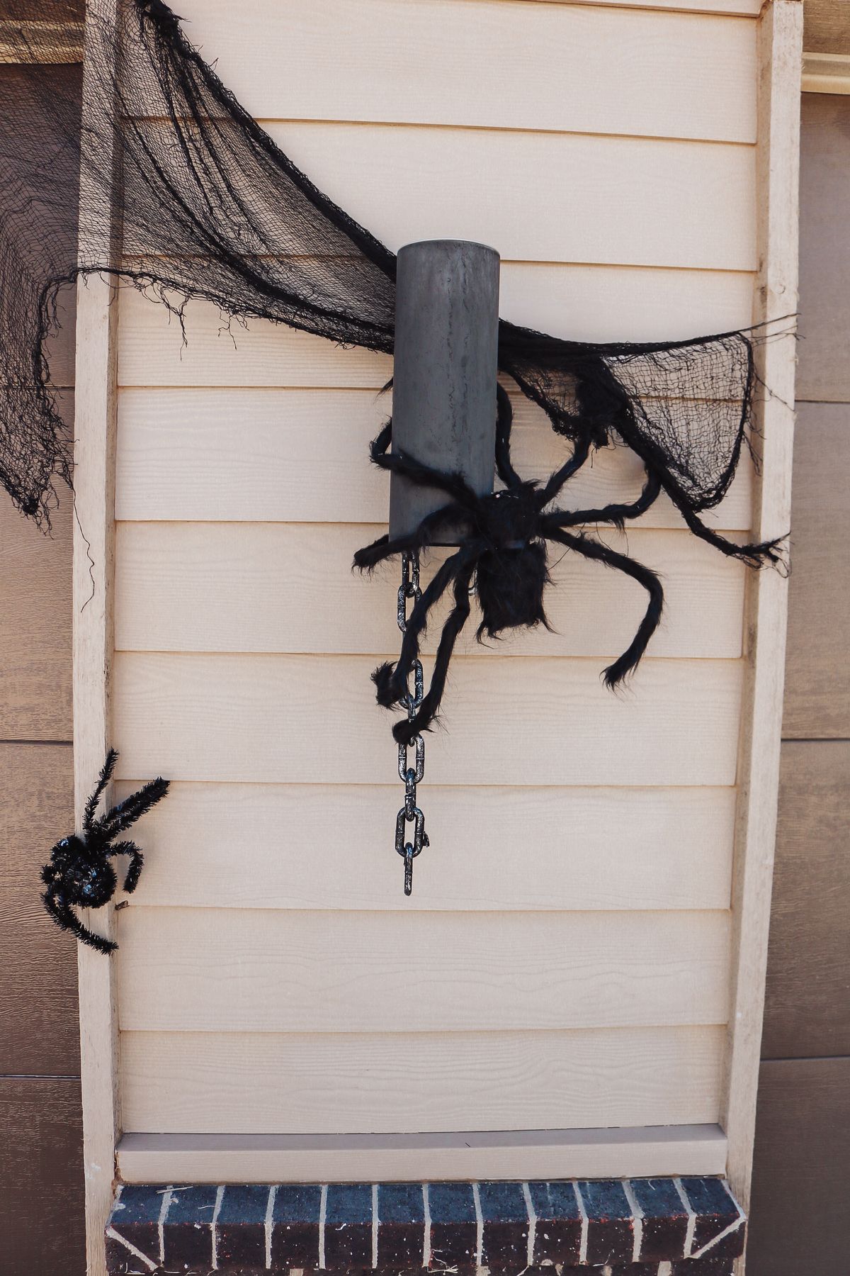 Spiders and black webbing on house siding for a spider Halloween porch