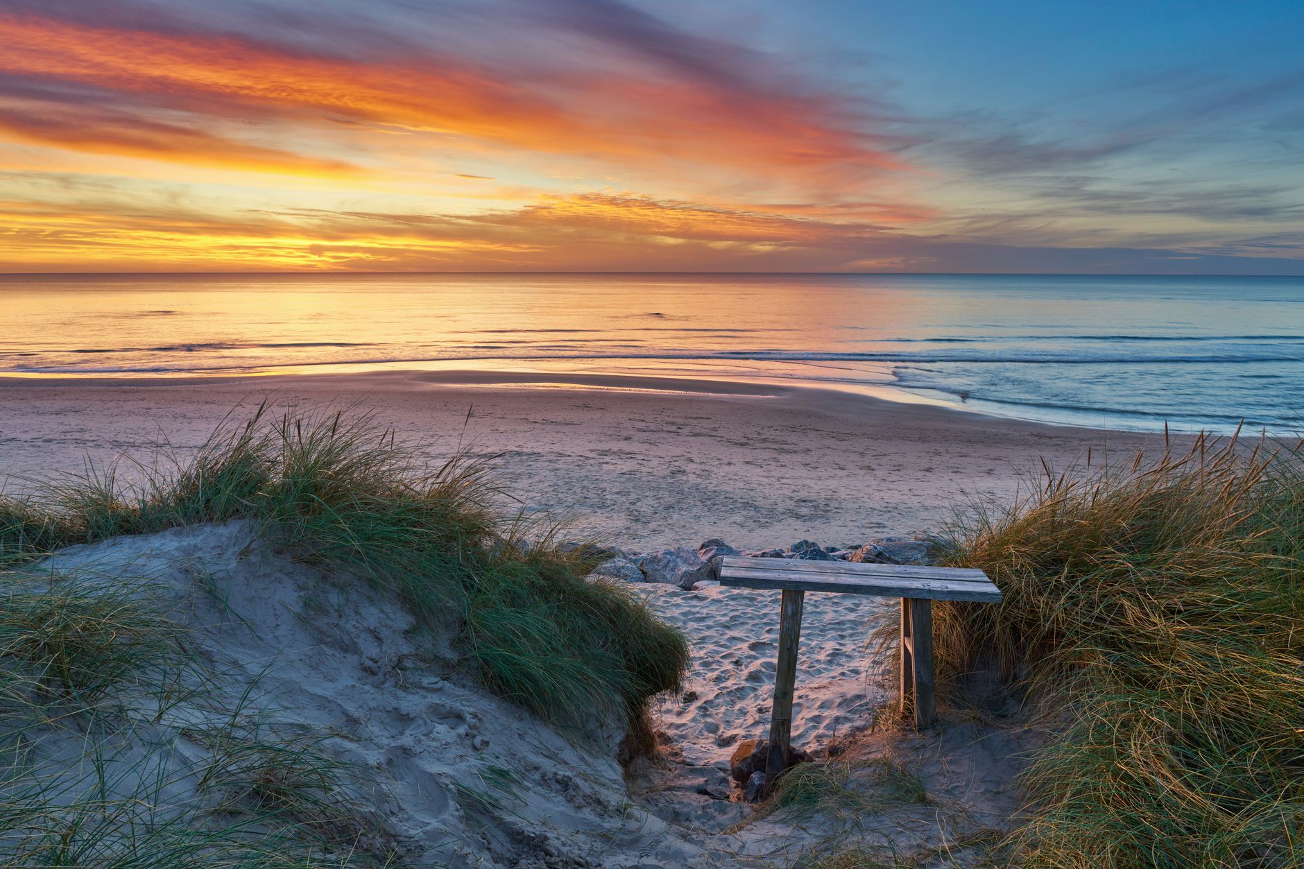 Captivating sunset over the serene sandy beach at Hjørring, Denmark, with vibrant sky and tranquil sea.