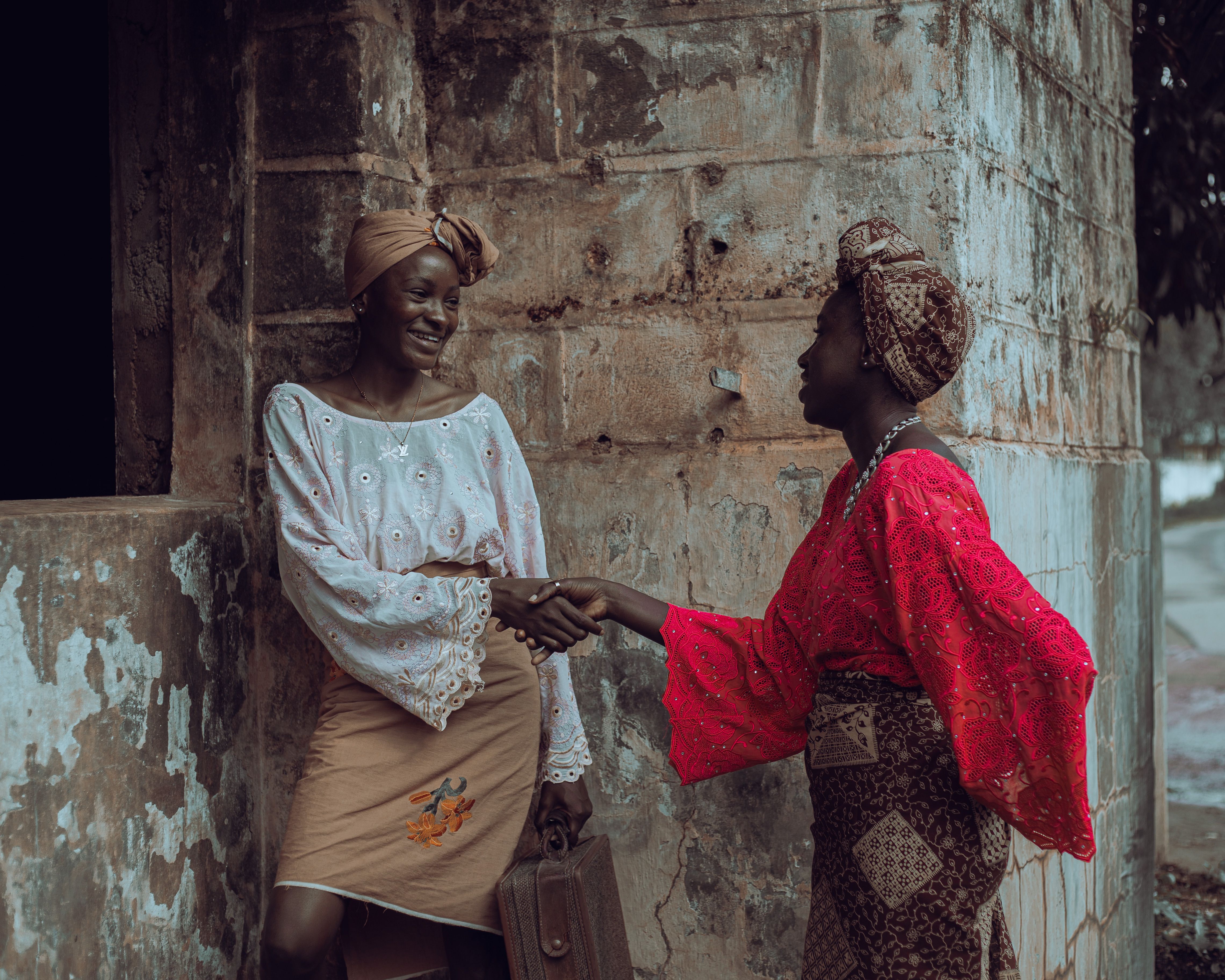 Two women in colorful traditional attire greeting each other
