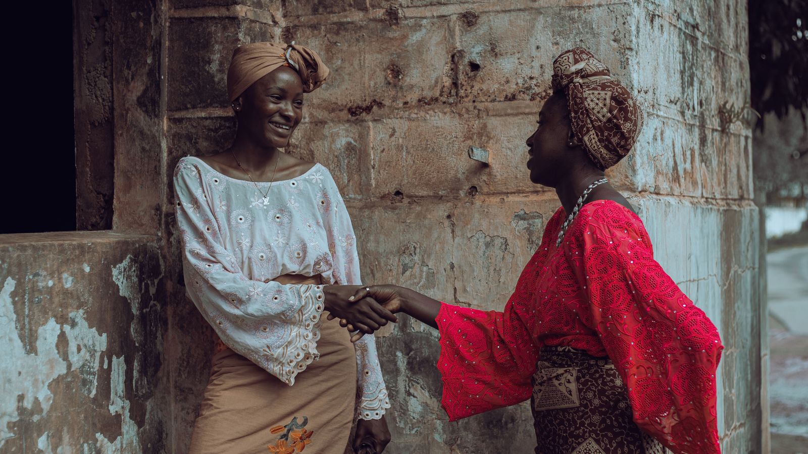 Two women in colorful traditional attire greeting each other