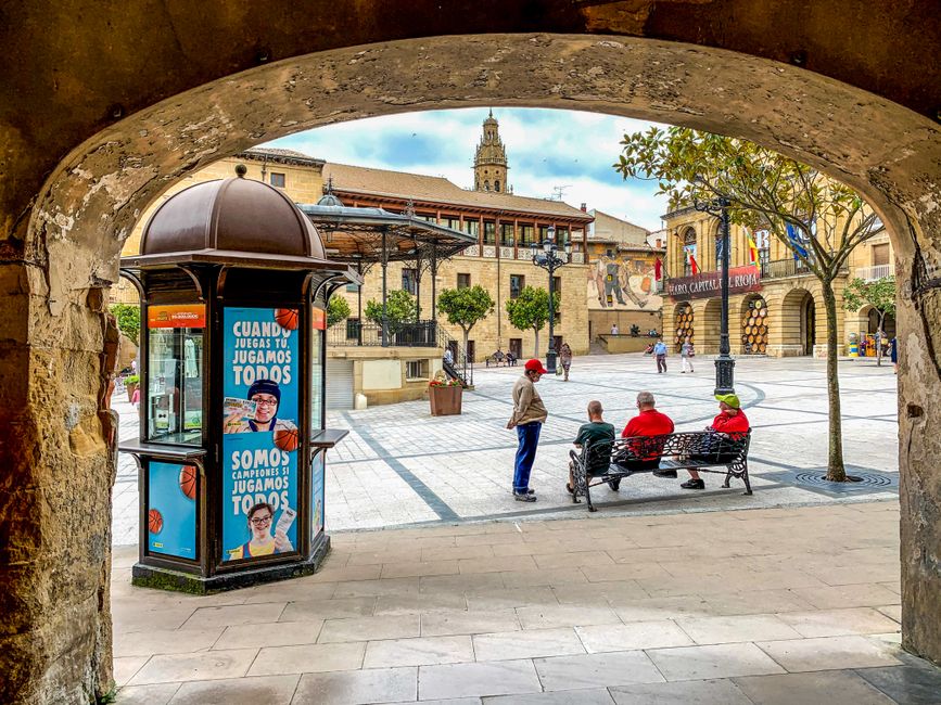Encantadora vista de una plaza en Haro, La Rioja, que muestra la arquitectura local y la gente disfrutando de un día soleado.