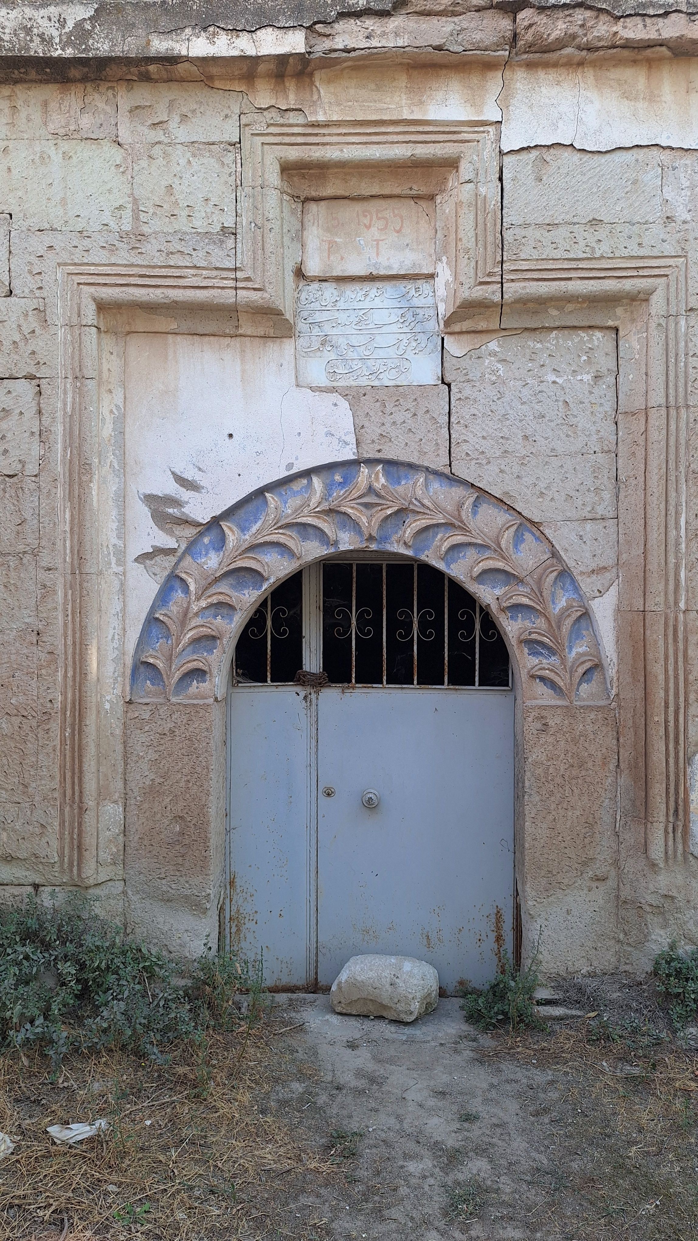 An ornate blue door set in weathered stone with intricate arch detailing.