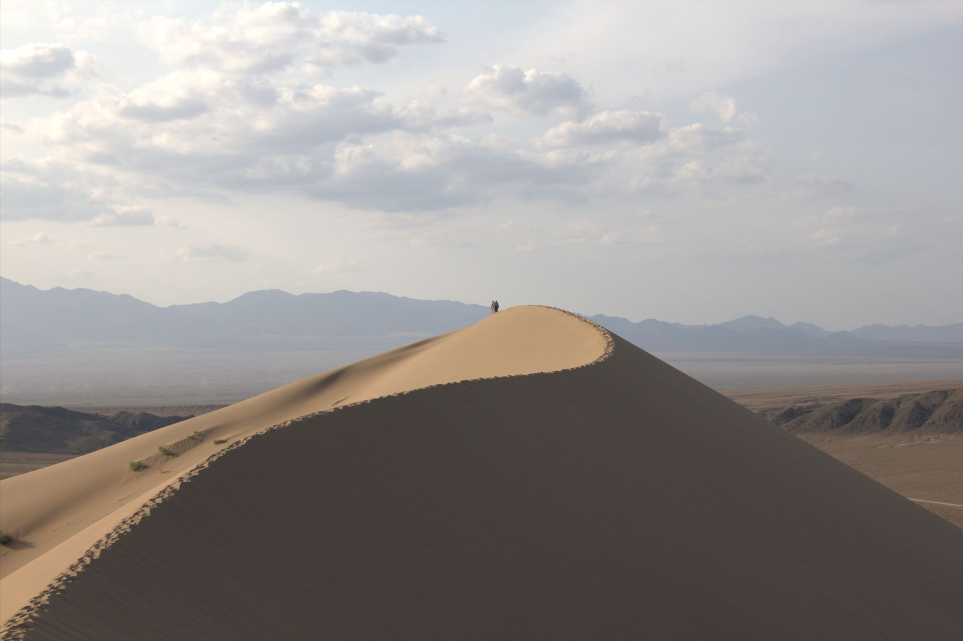 A breathtaking view of a sand dune in Almaty, Kazakhstan, under a cloudy sky, showcasing the vast desert landscape.. pexels,