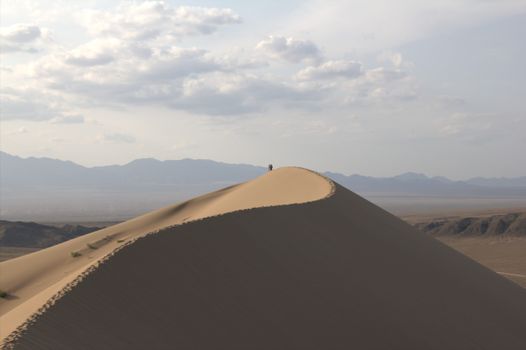 A breathtaking view of a sand dune in Almaty, Kazakhstan, under a cloudy sky, showcasing the vast desert landscape.. pexels, 