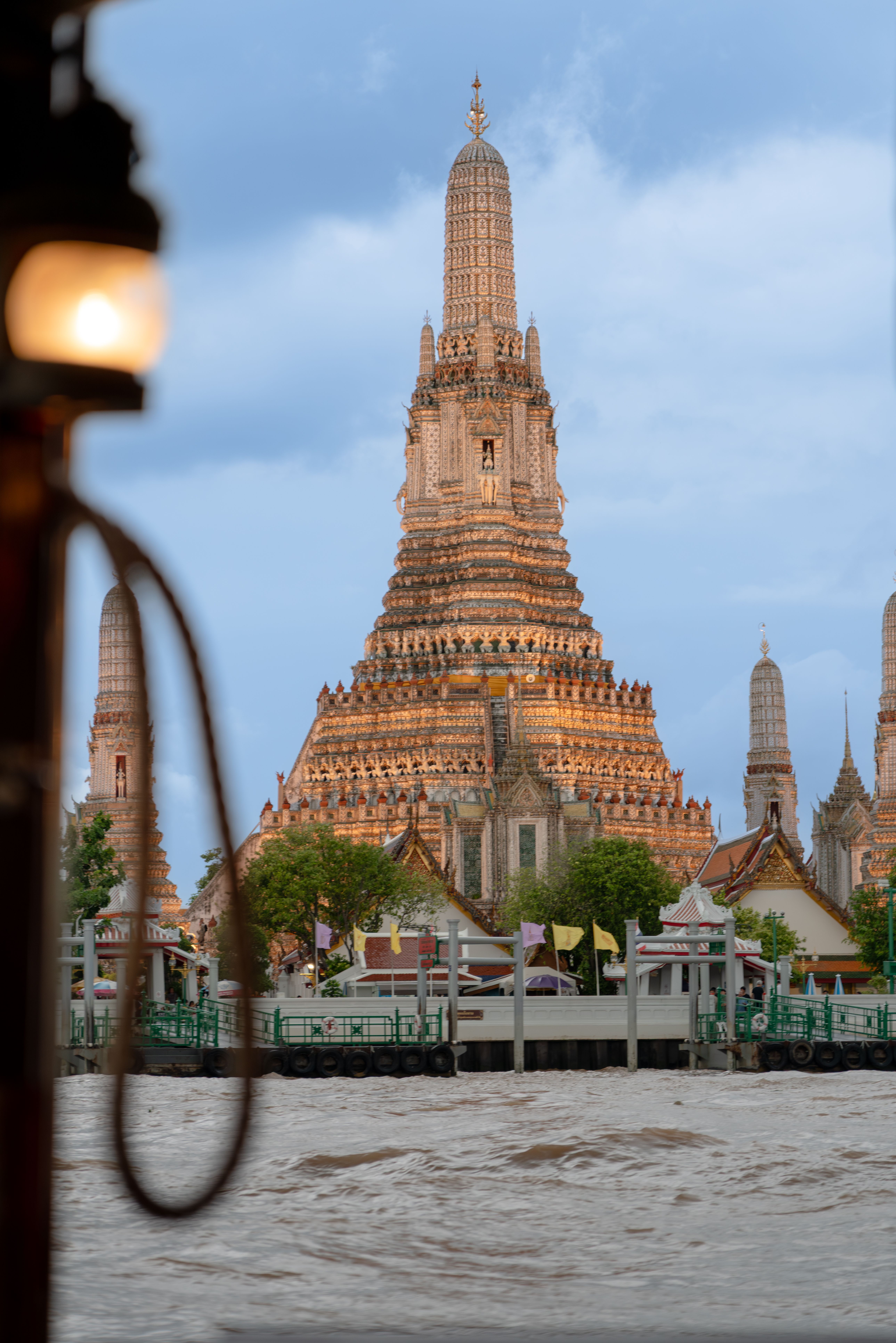 Wat Arun temple glowing at dusk on the Chao Phraya River in Bangkok, near The Peninsula Bangkok