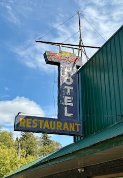 Old neon sign of a tourist hotel and restaurant against blue sky.