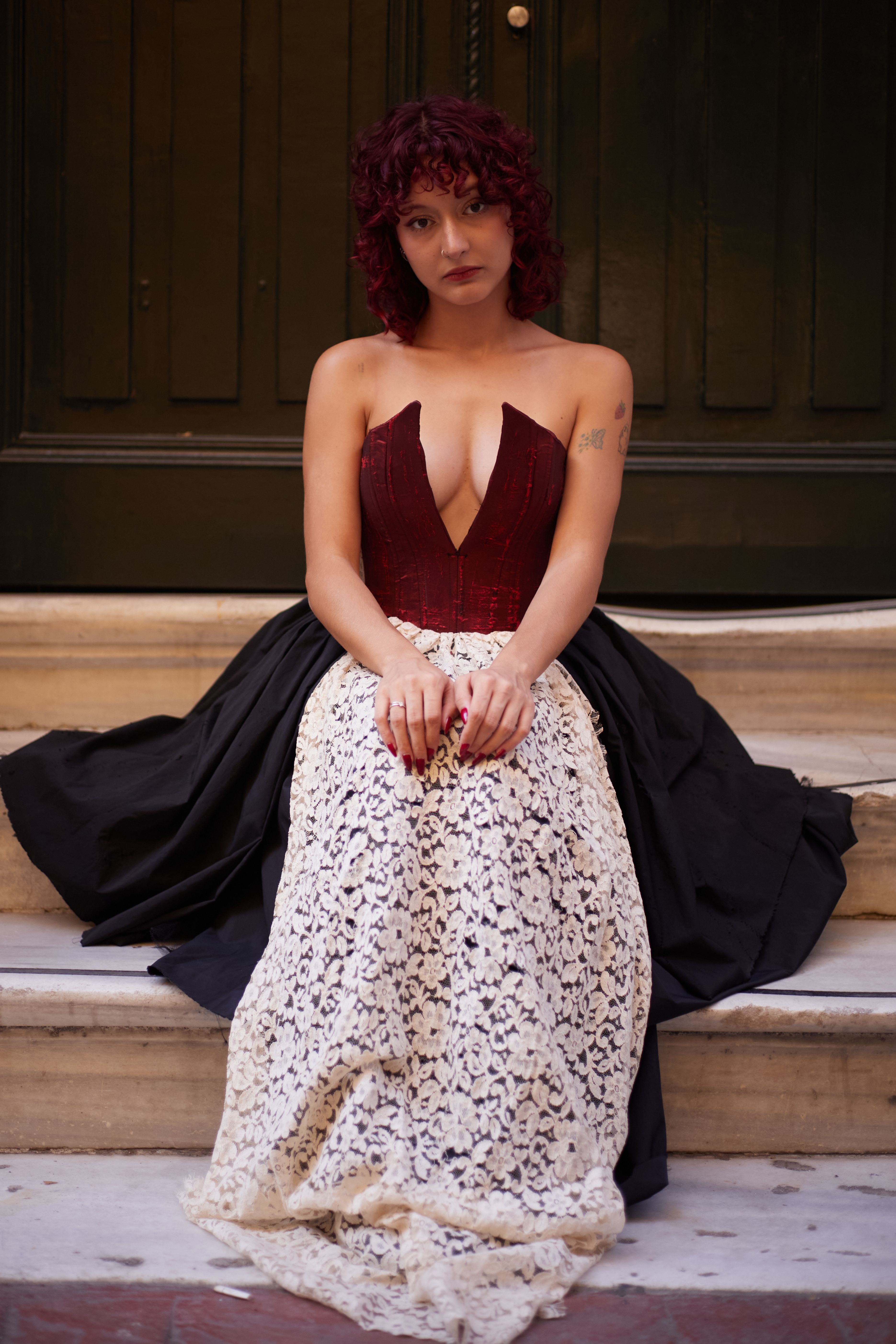 A woman in a stylish evening gown seated on marble steps in İstanbul.