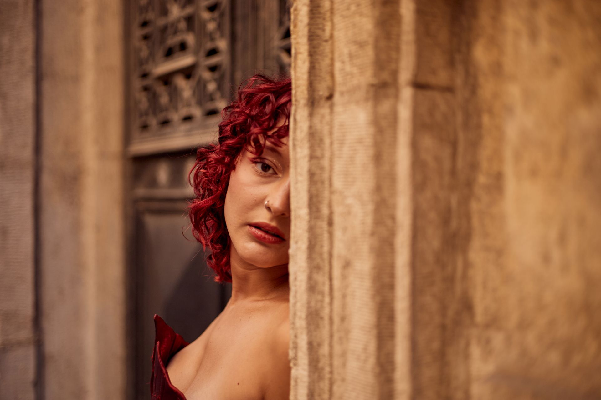 Captivating portrait of a woman with red hair peering from behind a wall in Istanbul.