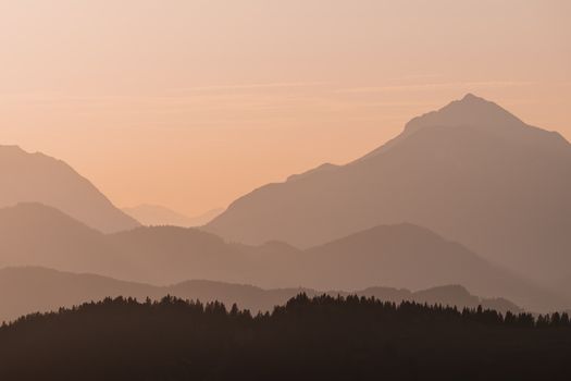 A tranquil sunrise view of layered mountains creating a peaceful and moody landscape.