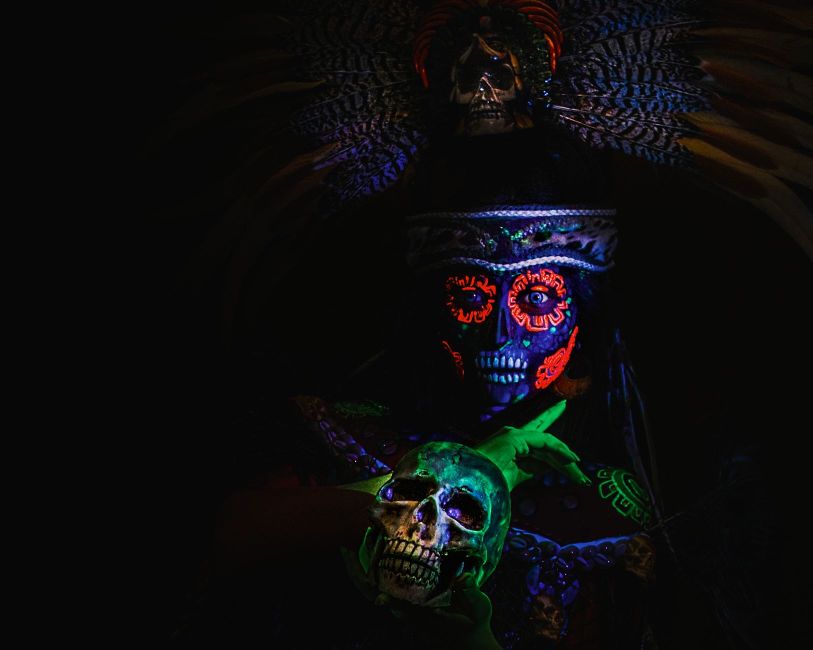 Aztec-inspired portrait with neon body paint and skull, embodying the vibrant Day of the Dead tradition in Mexico.