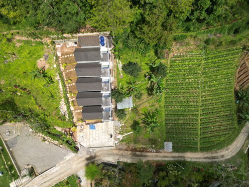 Free Aerial view of modern homestay cottages and farmland in the lush Indonesian countryside. Stock Photo