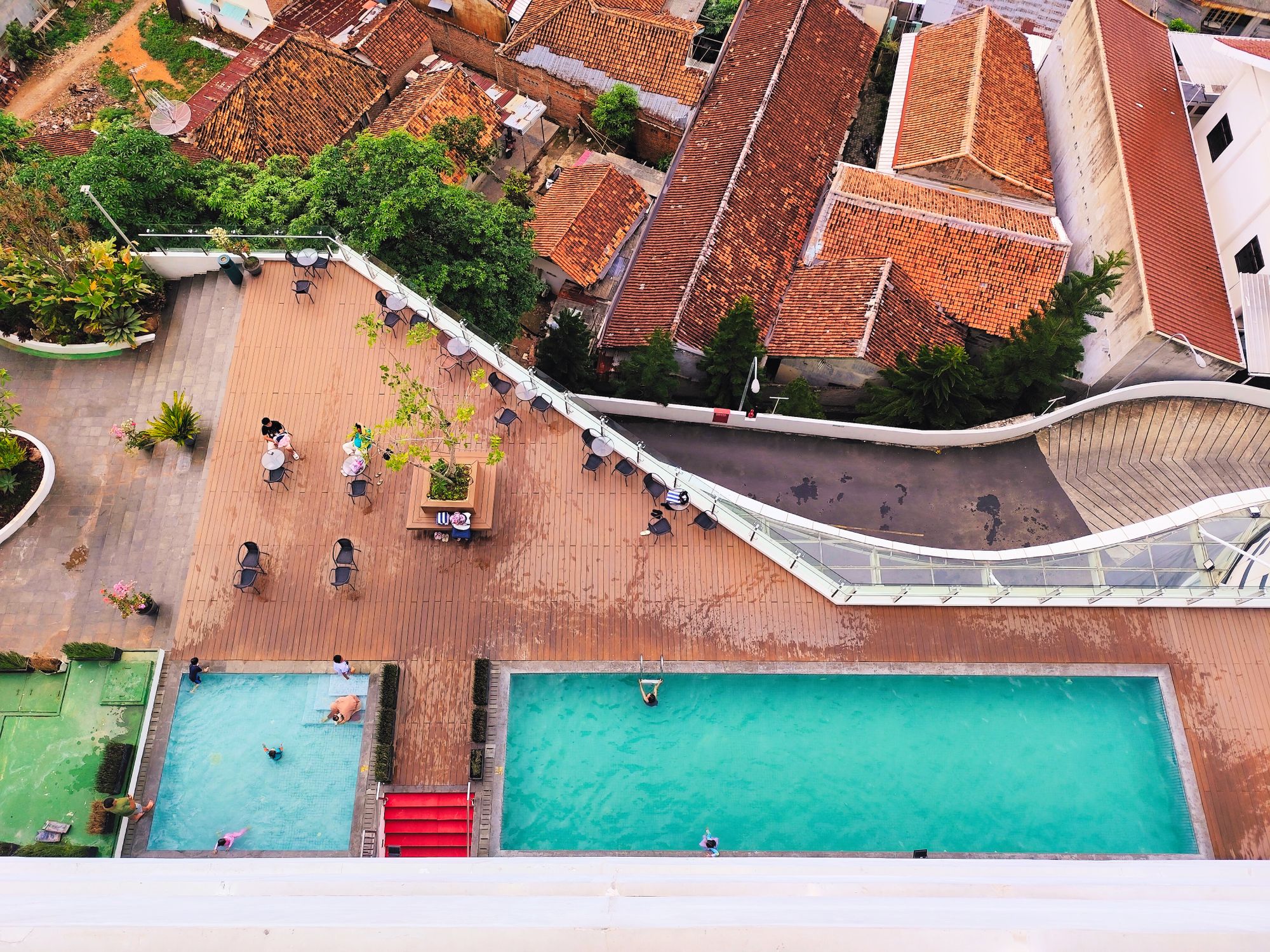 Aerial view of a rooftop pool area with swimmers and vibrant cityscape backdrop.