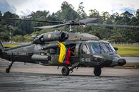 Colombian military helicopter on tarmac with national flag visible.