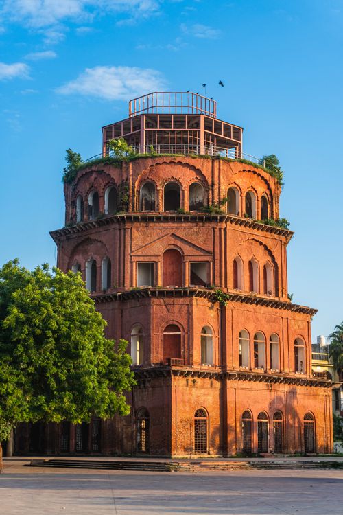 Free A striking red brick building with green vegetation against a clear blue sky, showcasing classic architecture. Stock Photo