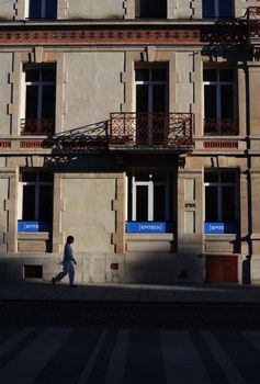 A lone man walks past the Epitech building in Nancy, France, during the day.