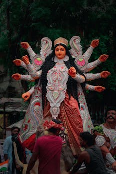 Vibrant statue of Goddess Durga with multiple arms during a traditional festival.