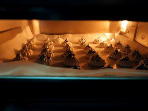Free Delicious meringue cookies baking in a warm oven with chocolate chips. Stock Photo