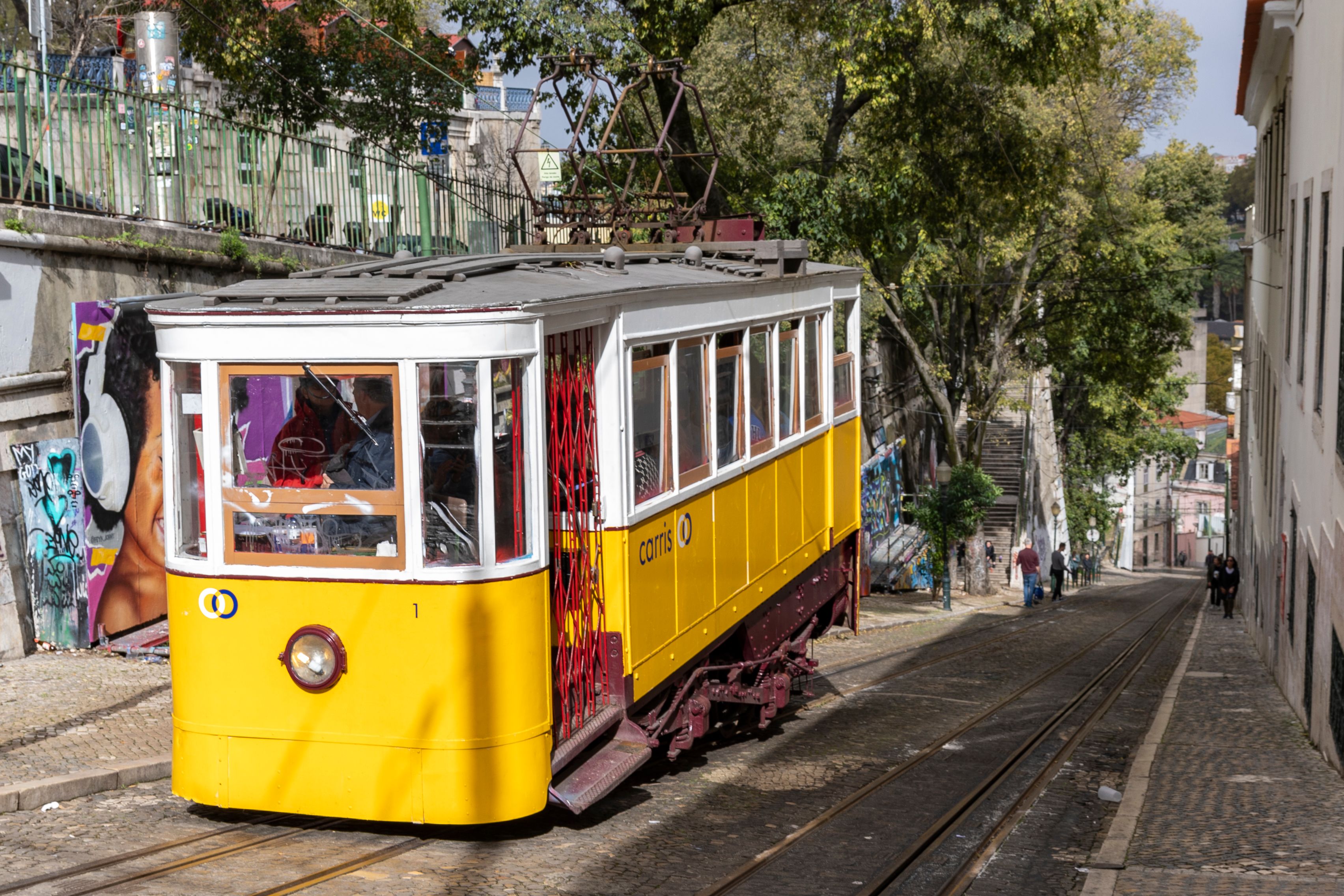 A classic yellow tram travels through a picturesque street in Lisbon, capturing the charm of the city.