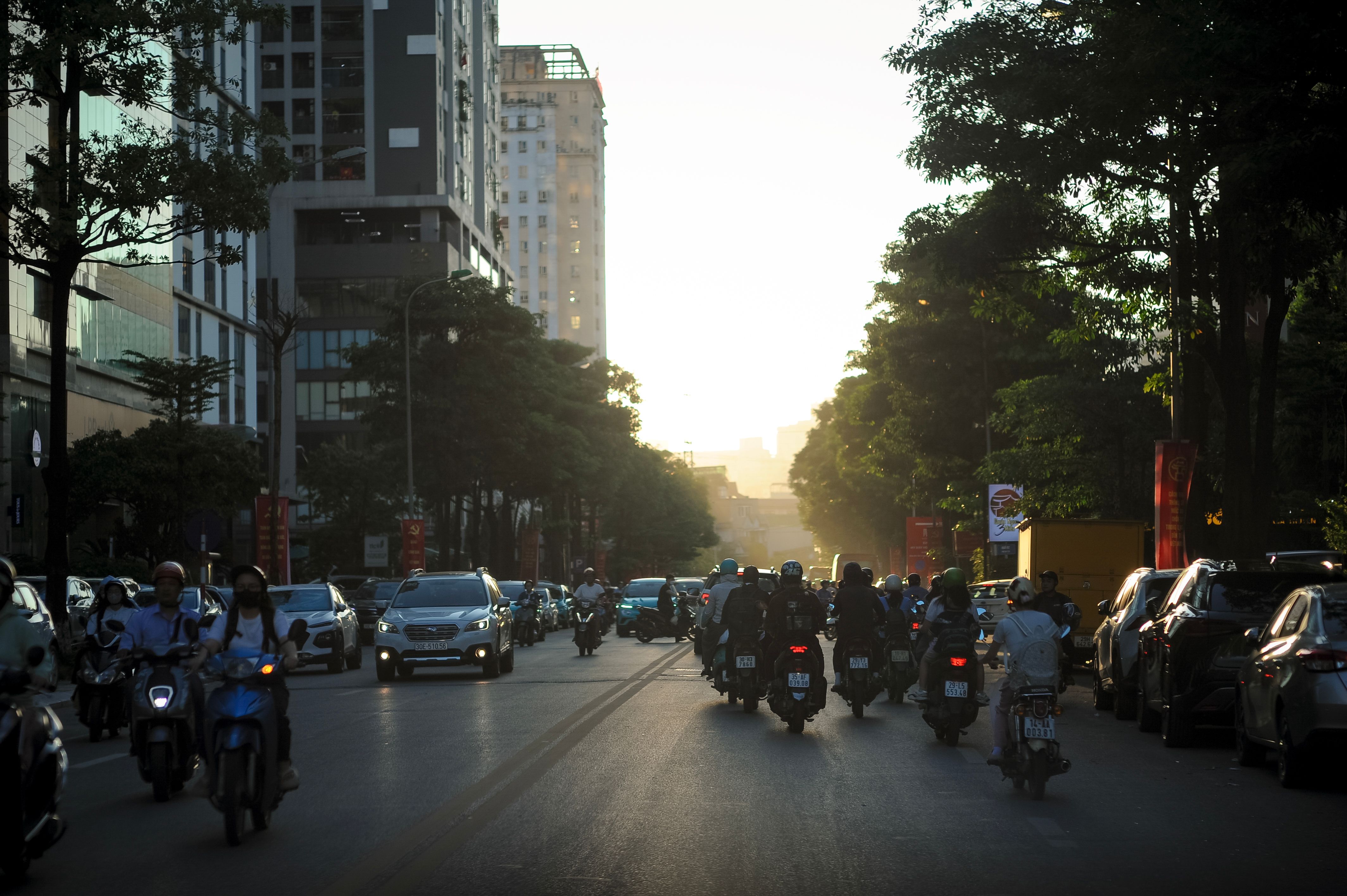 Calle de Hanói al atardecer con tráfico intenso de motos y coches