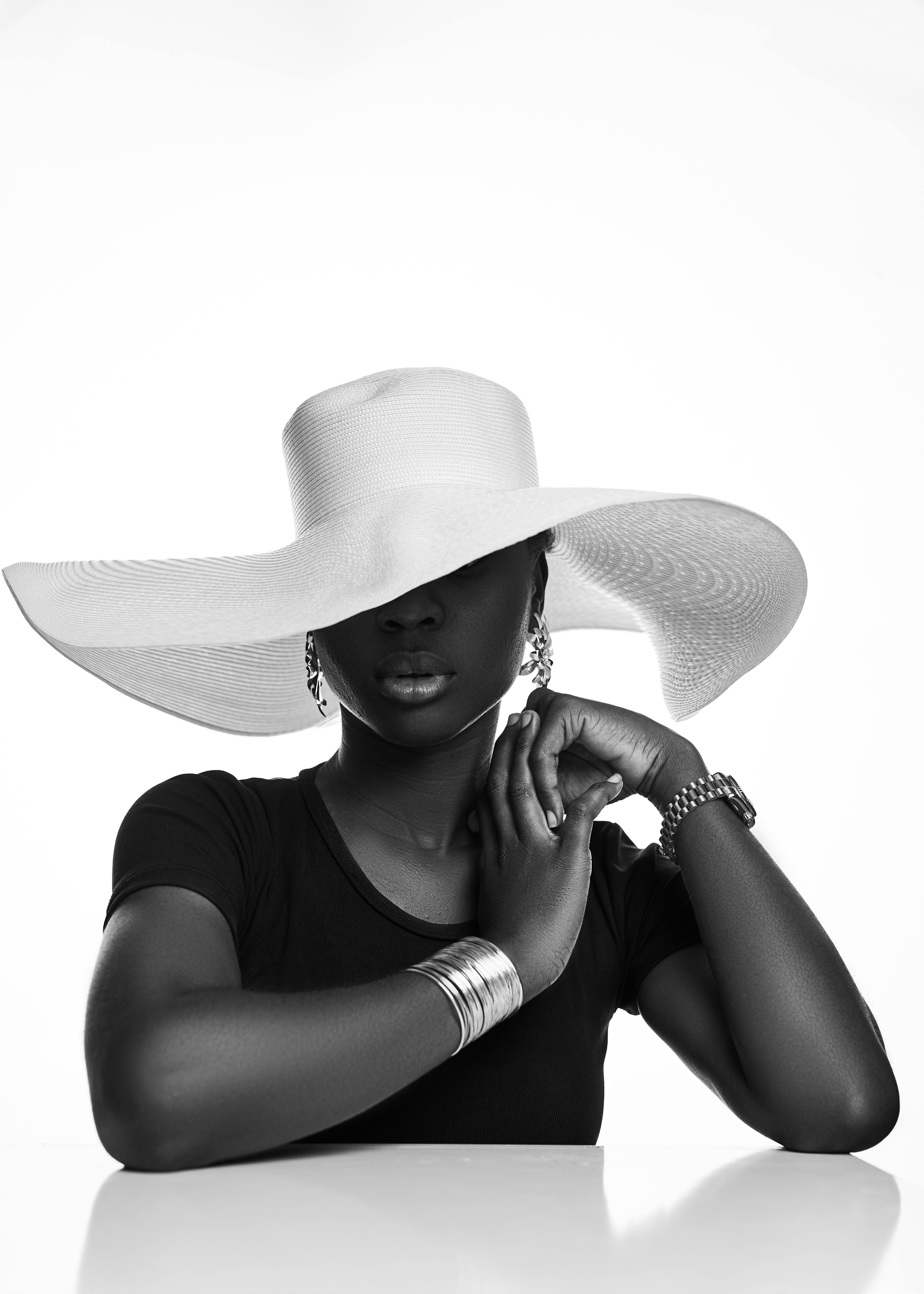 Black and white portrait of a woman wearing a chic wide-brimmed hat, exuding elegance.