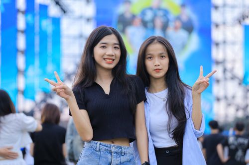 Free Two young women pose happily at an outdoor event in Hanoi, Vietnam, making peace signs. Stock Photo