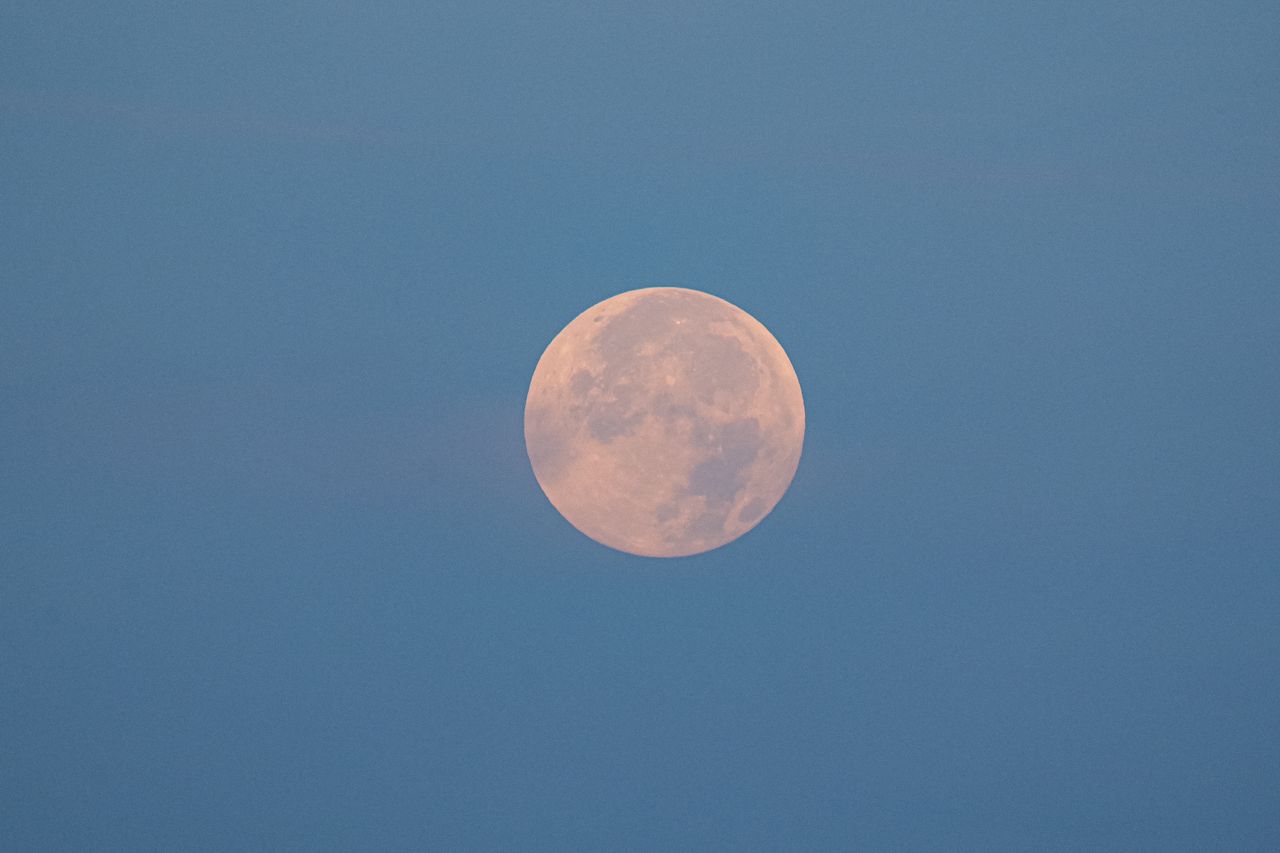 captivating full moon against a serene blue sky during twilight showca