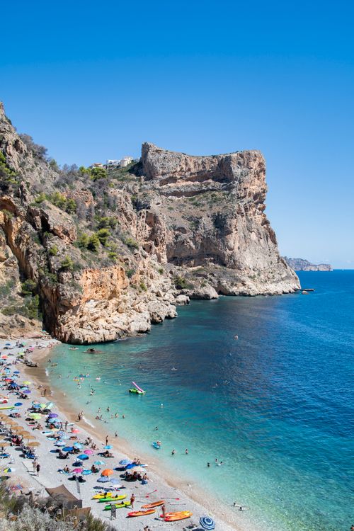 Free Idyllic beach with rocky cliffs and turquoise sea in summer, perfect for travel inspiration. Stock Photo