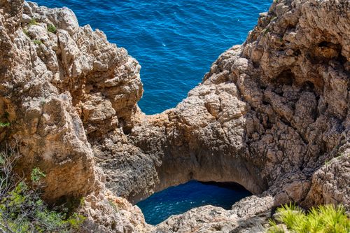 Free Dramatic rocky coastline with natural arch overlooking the vibrant blue ocean. Stock Photo