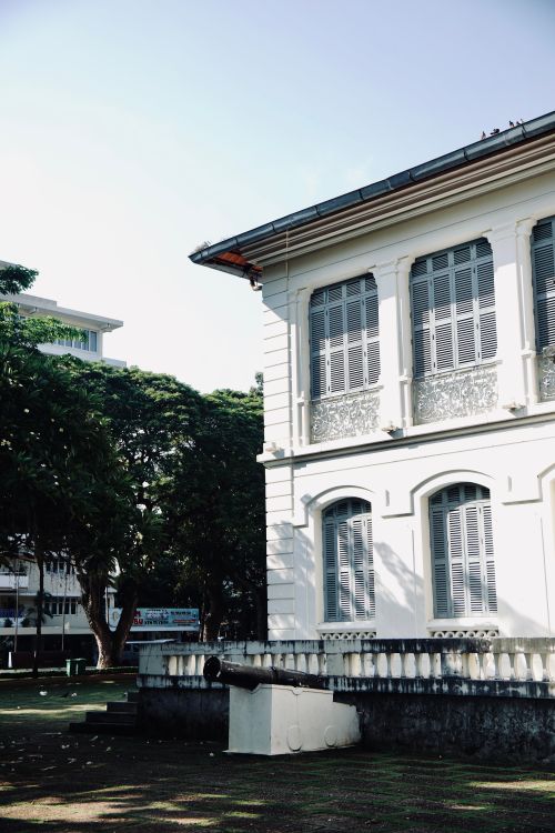 Free Elegant colonial-style building with classic shuttered windows and sunlight casting shadows. Stock Photo
