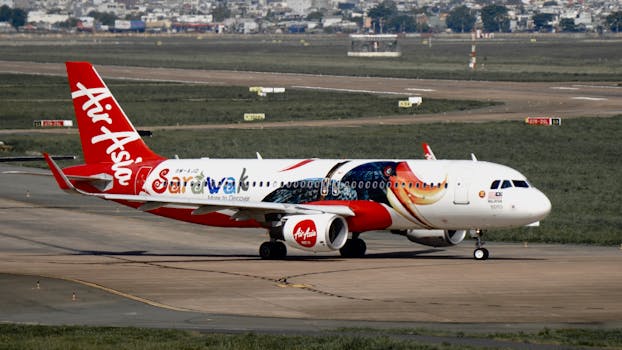 AirAsia plane with Sarawak design taxis on airport runway, sunny day.