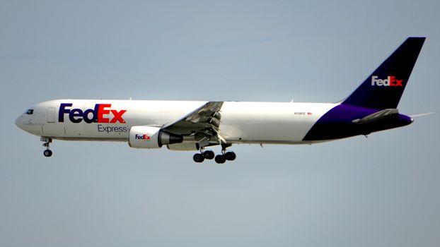 A FedEx cargo plane captured in mid-flight against a clear blue sky, showcasing air logistics.