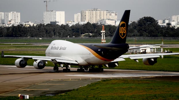 UPS cargo aircraft taxiing on runway at an airport with cityscape background.