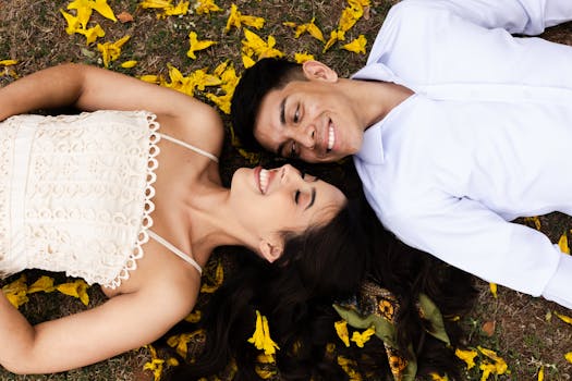 A couple in love lies on yellow petals in a park in São Paulo, Brasil, capturing an affectionate moment.