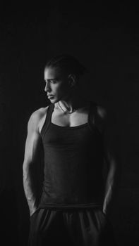 A dramatic black and white portrait of a man in a tank top, looking sideways.