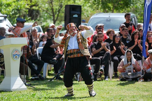 Elderly man in traditional Turkish attire dancing at an outdoor festival in Antalya.