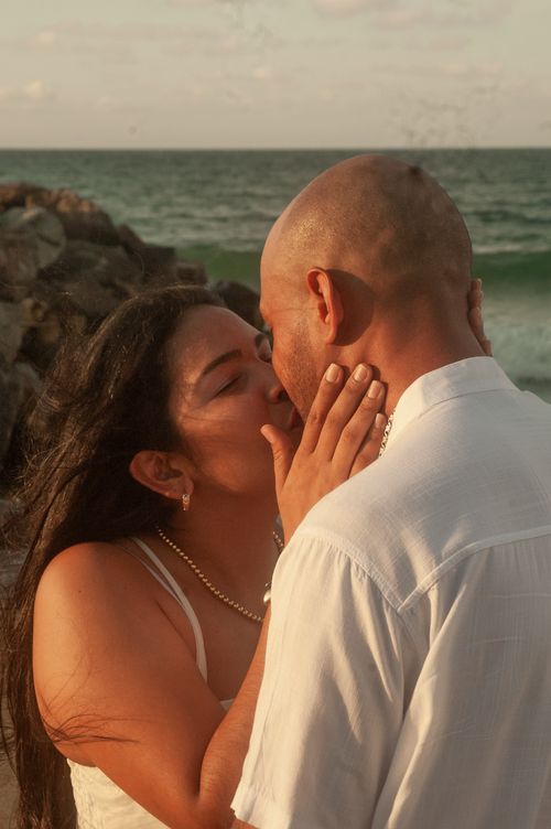 Free A romantic scene of a couple kissing by the ocean, capturing love and intimacy. Stock Photo