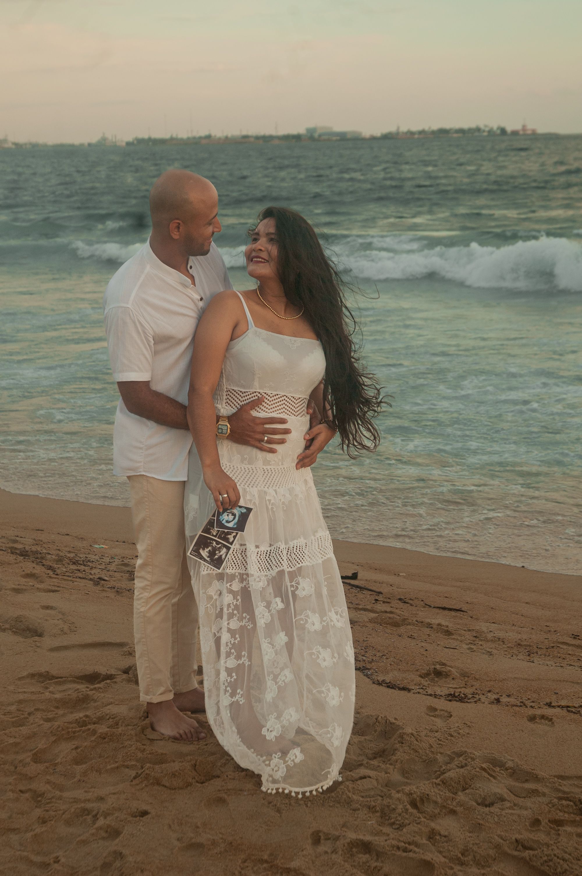 Smiling couple in coats on a windy beach