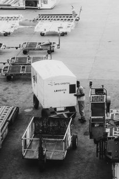 Black and white photo of airport ground crew managing cargo equipment.