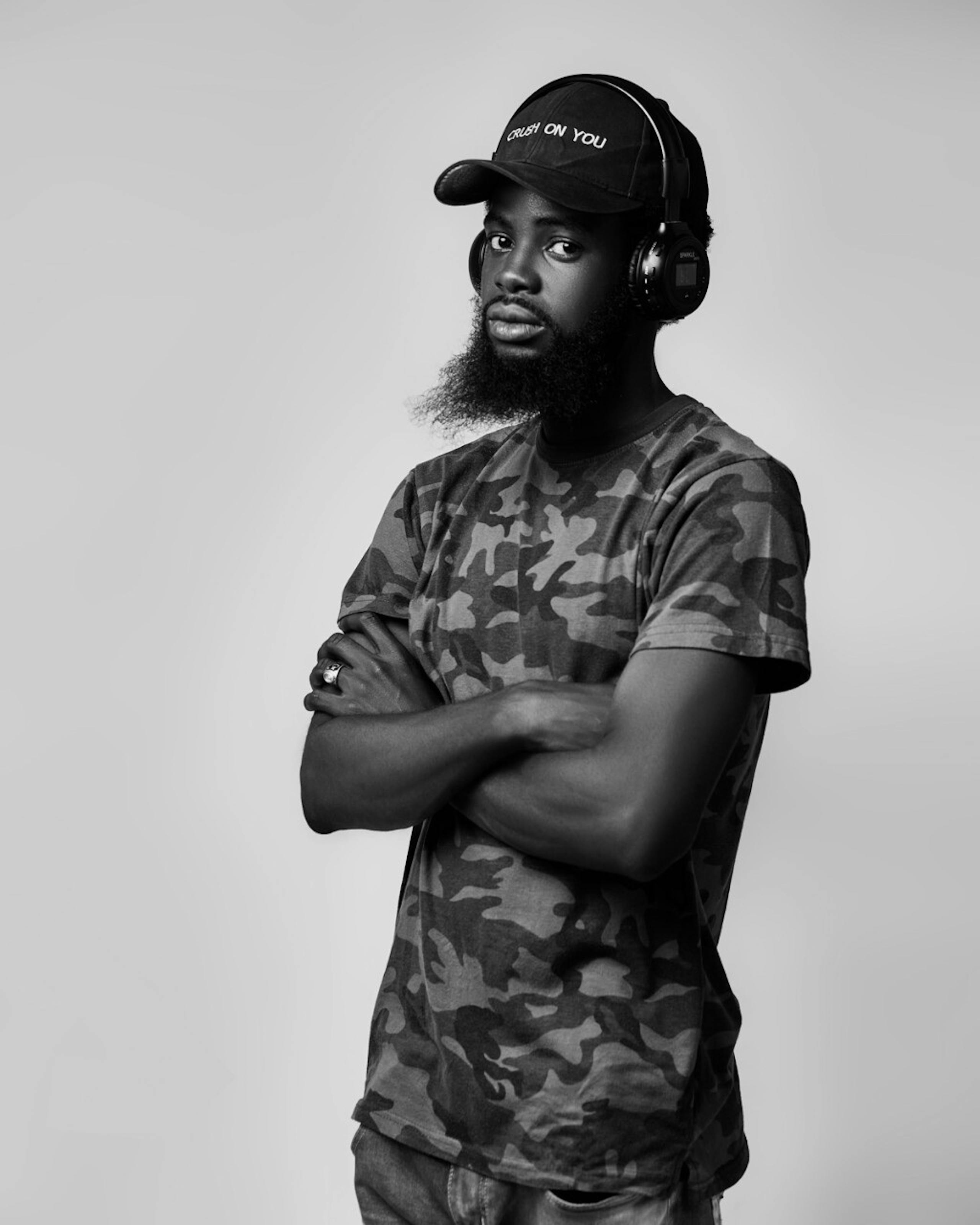 Free Black and white portrait of a man wearing a camouflage T-shirt and headphones, captured with a modern, artistic style. Stock Photo
