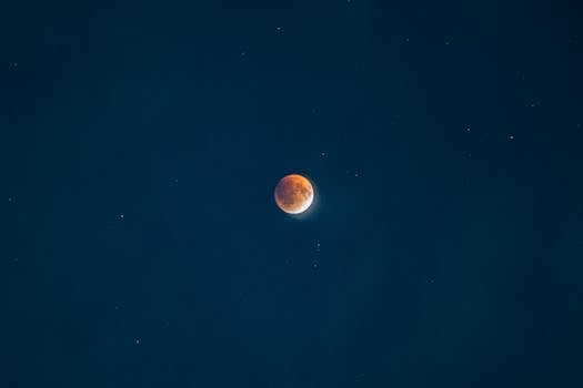Captivating view of a blood moon during a lunar eclipse with stars in the night sky.