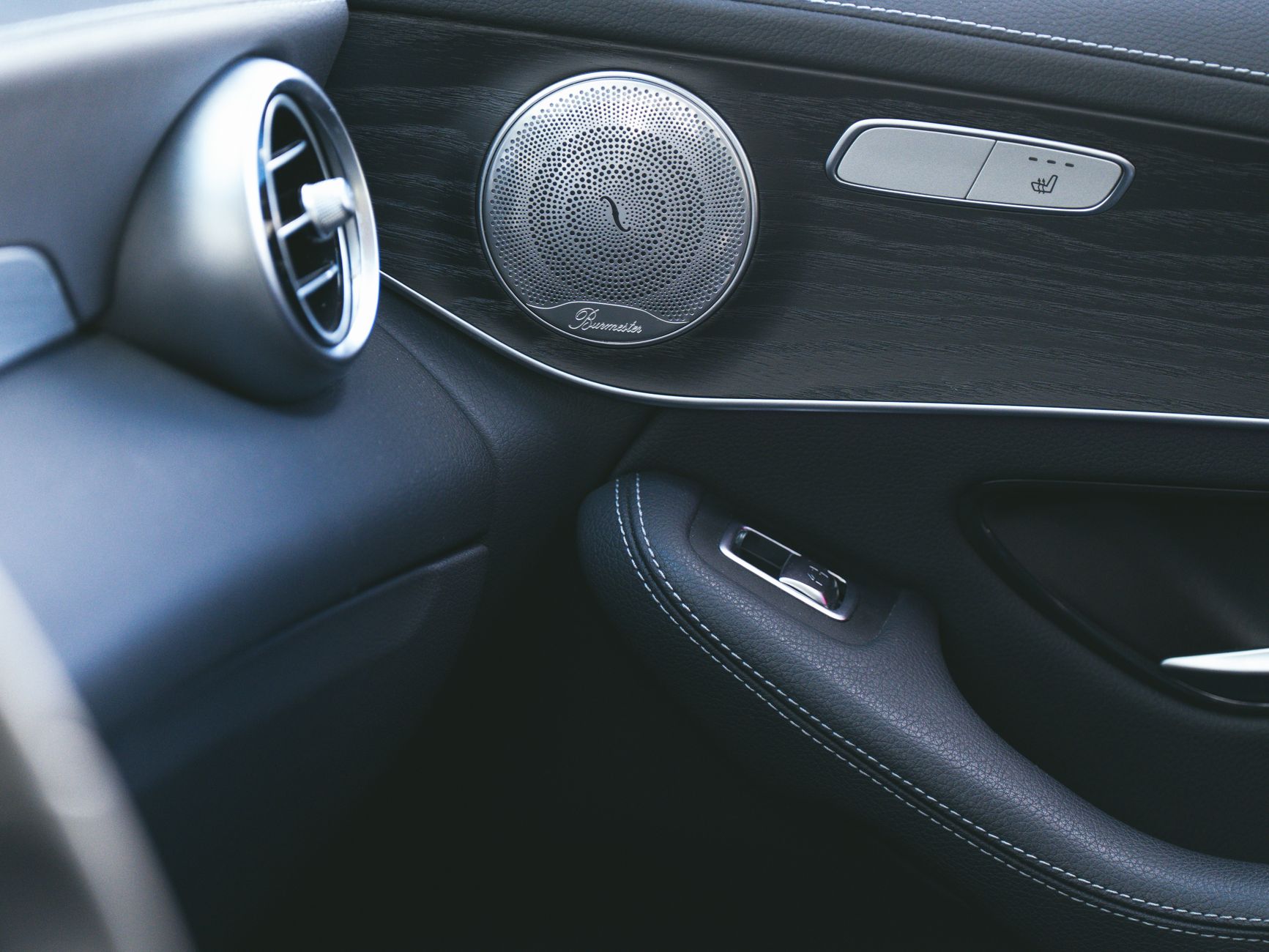 Close-up of a luxury car's sleek interior showcasing a premium speaker and air vent design.