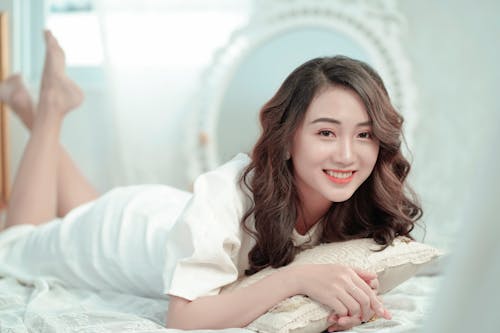 Free Photo of Smiling Woman Lying Down on a Bed Posing Stock Photo