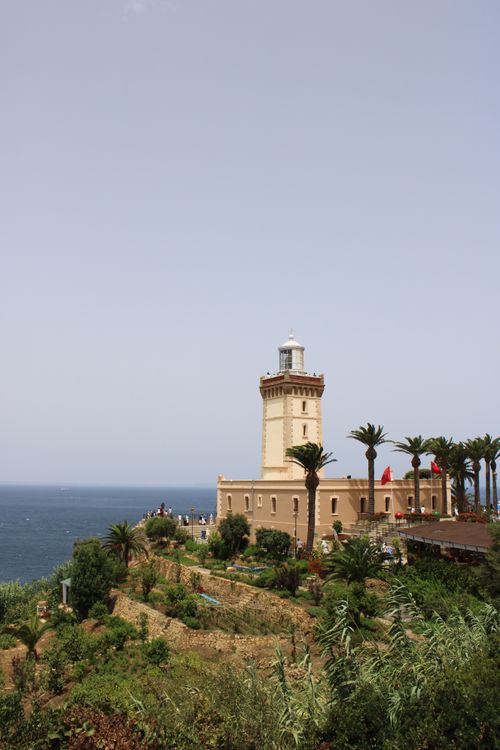 Free Cap Spartel Lighthouse stands tall above lush greenery with a stunning view of the Atlantic Ocean in Tangier, Morocco. Stock Photo