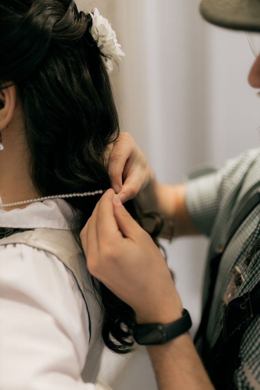 Groom adjusting a necklace on a bride