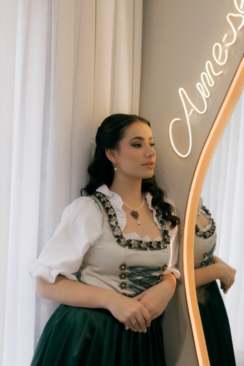 Free Young woman in traditional attire posing beside a mirror with elegant lighting. Stock Photo