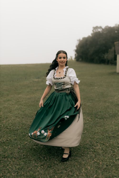 Free Young woman in a traditional Bavarian dress twirling in a grassy field. Stock Photo